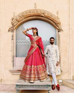 white groom sherwani & red bridal lehenga